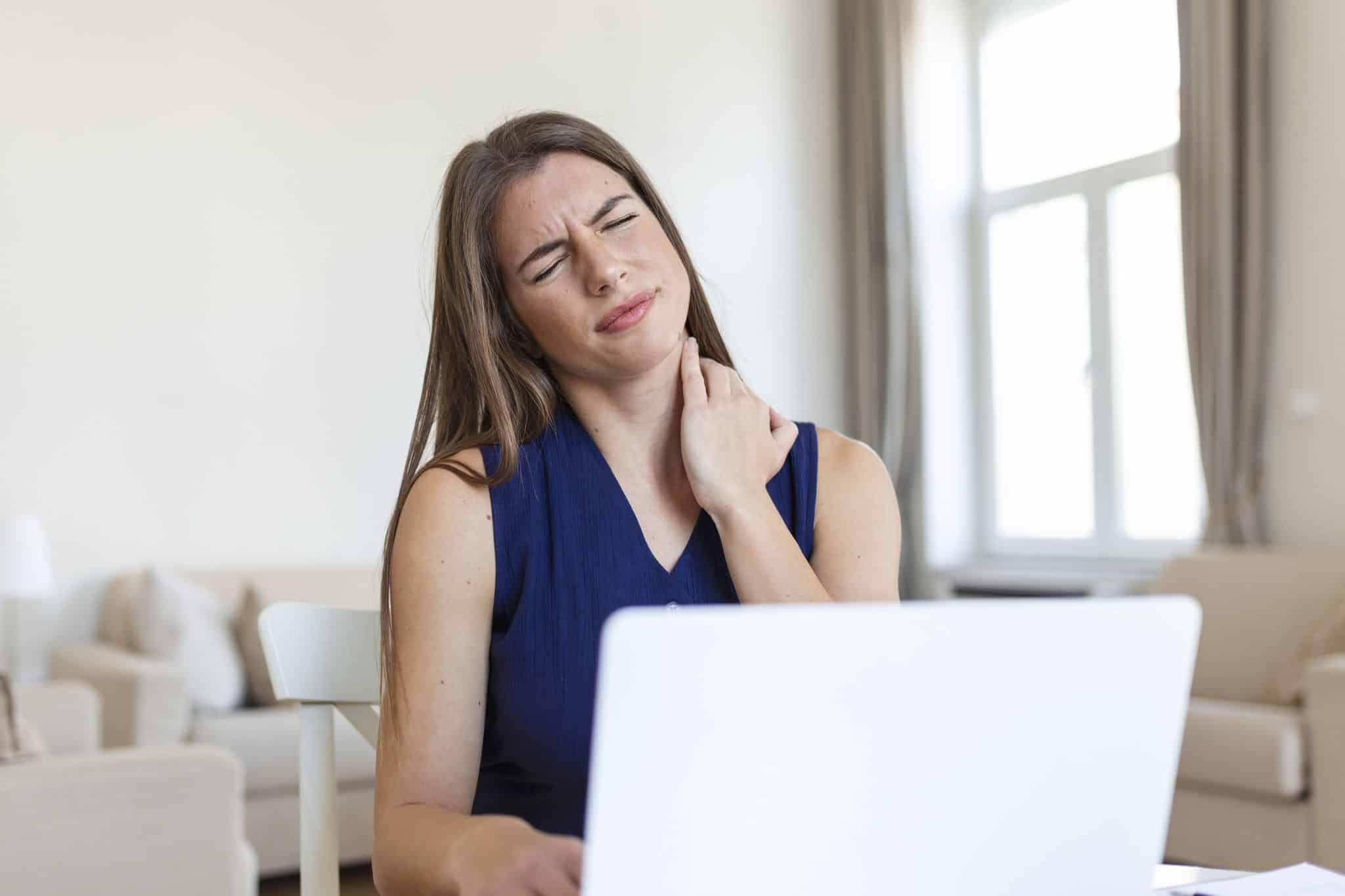 young businesswoman suffering from neckache massaging her neck while sitting her working place home office